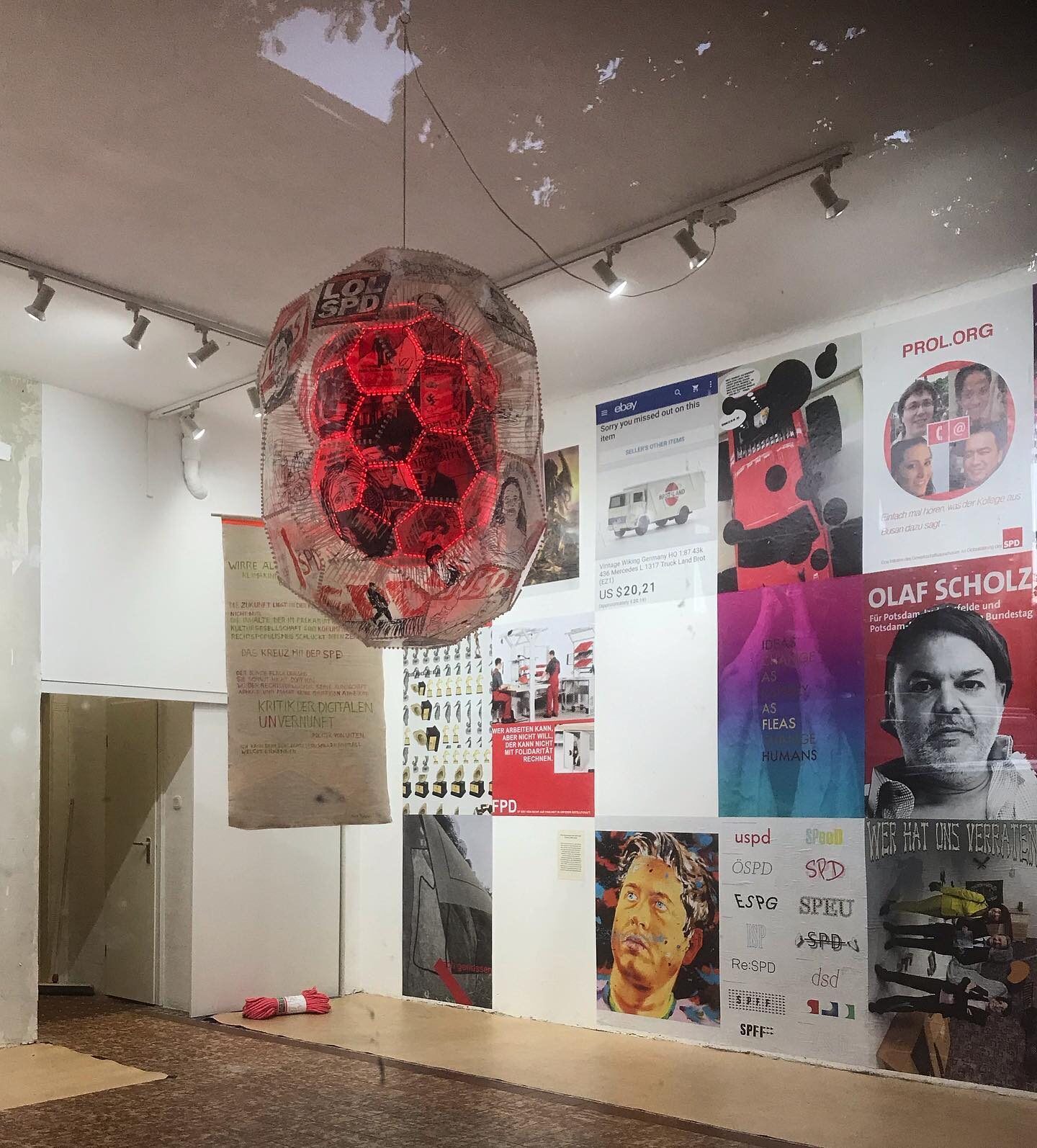 «Die Zukunft der SPD #2» — Lichtobjekt im Raum mit Plakatwand (Olaf Scholz, PROL.ORG, IDEAS CHANGE AS RAPIDLY AS FLEAS CHANGE HUMANS)