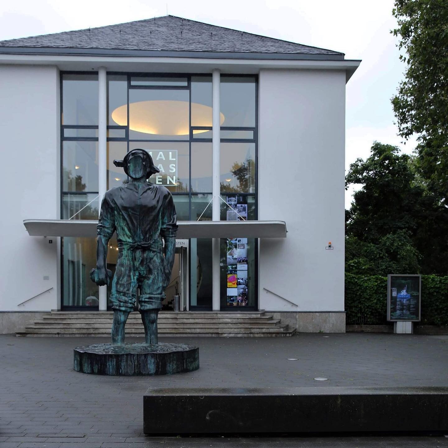 «Malkasten revisited» — Vorplatz mit Bronze-Skulptur und Blick auf das Jacobihaus bei Dämmerung