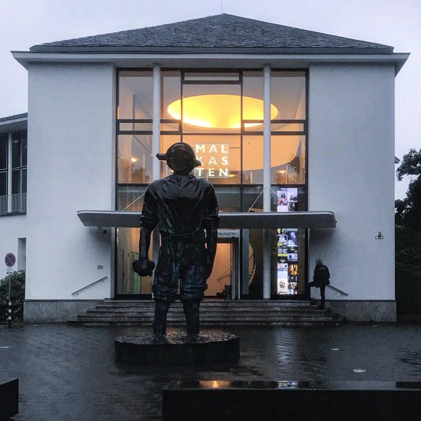 «Malkasten revisited» — Bronze-Skulptur vor dem beleuchteten Jacobihaus im Regen